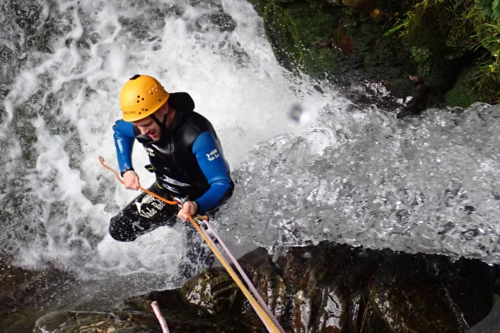 a man abseiling down a waterfall