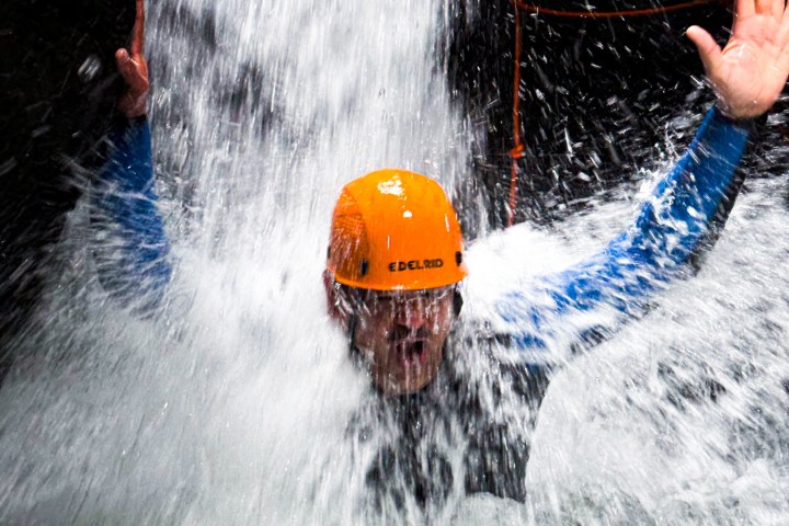 A man testing the power of the waterfall