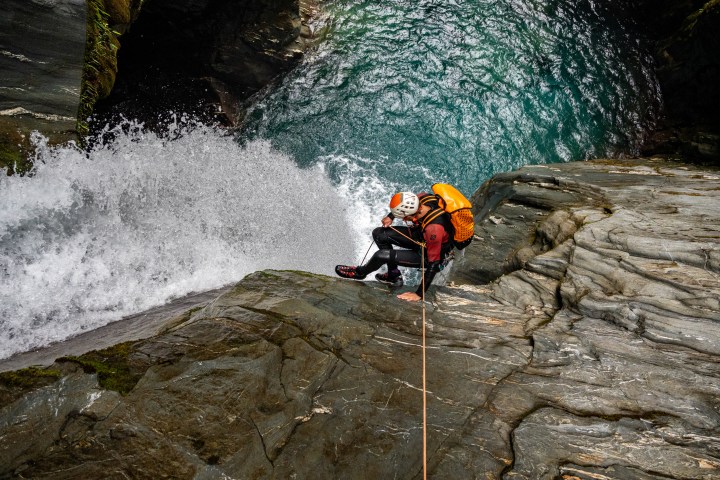 Two climbers in gear rappel down a rocky waterfall.