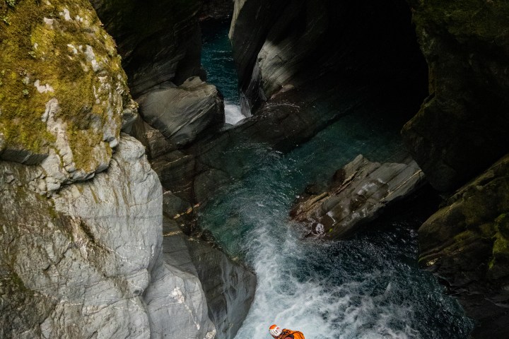 Person rappelling down a rocky waterfall in a gorge.