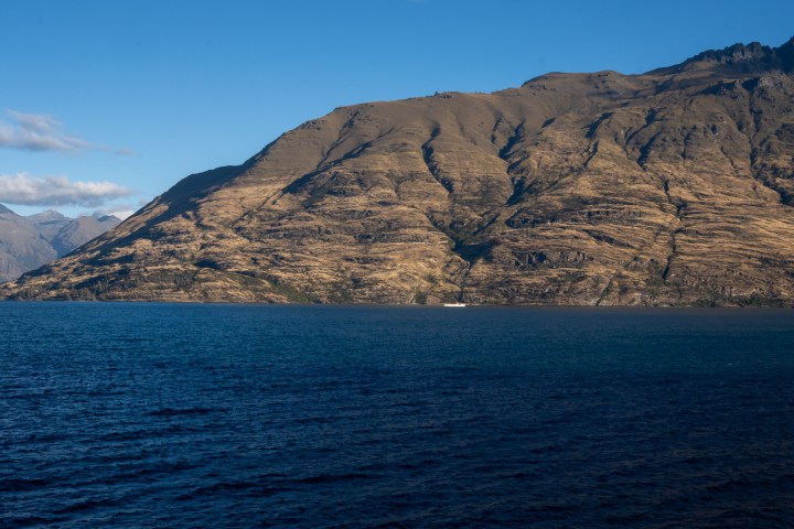 Large mountain beside a calm blue lake under a clear sky.