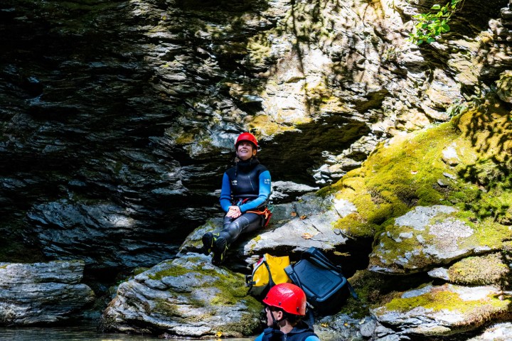 Two people in wetsuits and helmets in a rocky stream.
