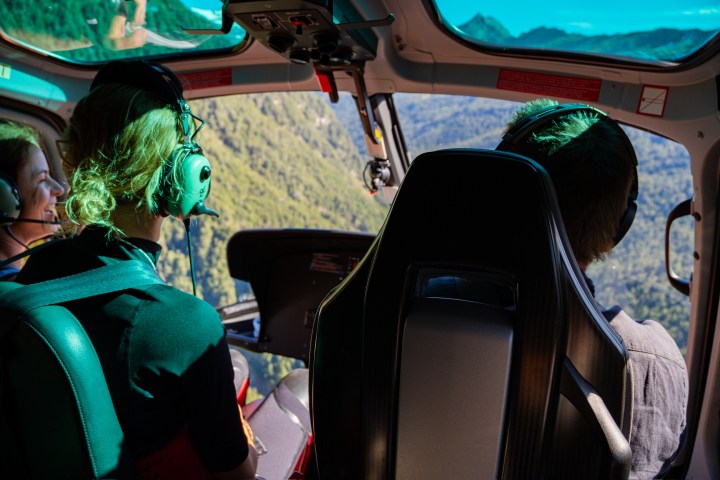 People inside a helicopter with a view of mountains through the windshield.