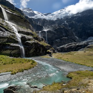 Mountain valley with cascading waterfalls and a winding river.