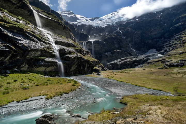 Mountain valley with cascading waterfalls and a winding river.